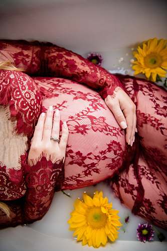 united states pregnant woman laying on tub with water and flowers cushion